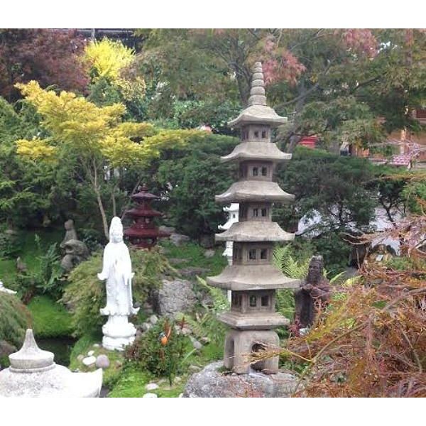 A serene Japanese garden showcasing a traditional stone pagoda and a white Buddha statue amidst lush greenery, providing a tranquil and spiritual atmosphere.