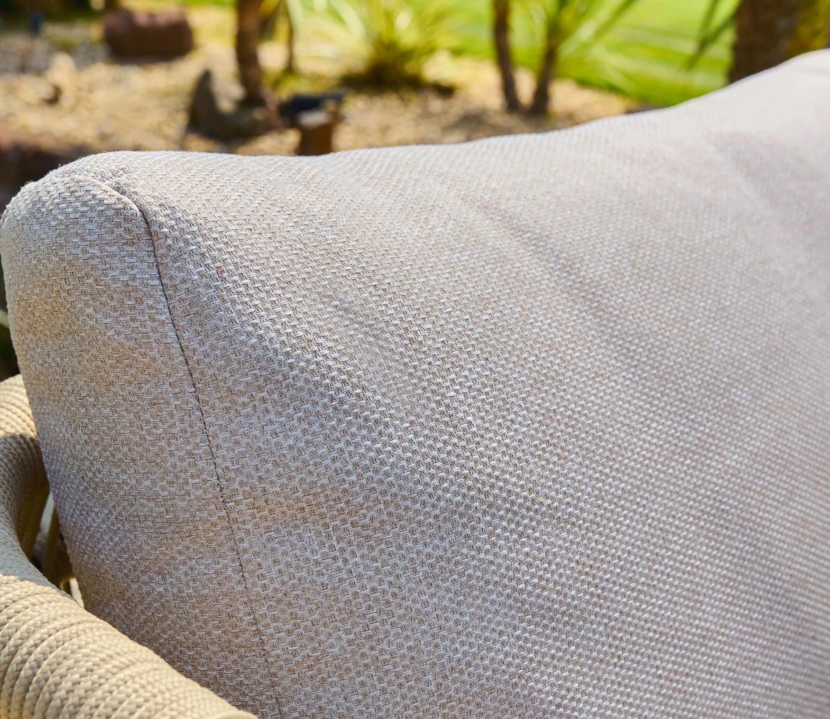 Cream-textured outdoor sofa cushion detail with a subtle woven pattern. The light shade complements natural settings, enhancing garden or patio aesthetics.