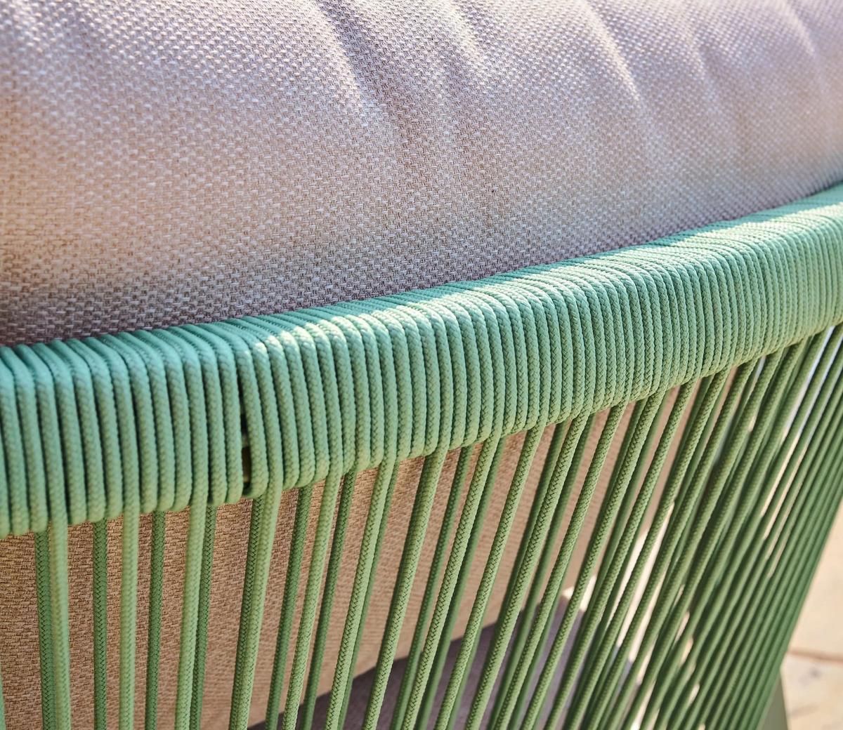 Close-up of a green woven chair backrest with detailed rope design, paired with a textured beige cushion, ideal for outdoor patio furniture settings.