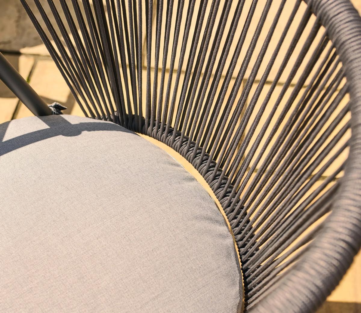 Stylish outdoor chair with grey woven rope backrest and matching fabric cushion on stone patio. Ideal for gardens and contemporary outdoor spaces.