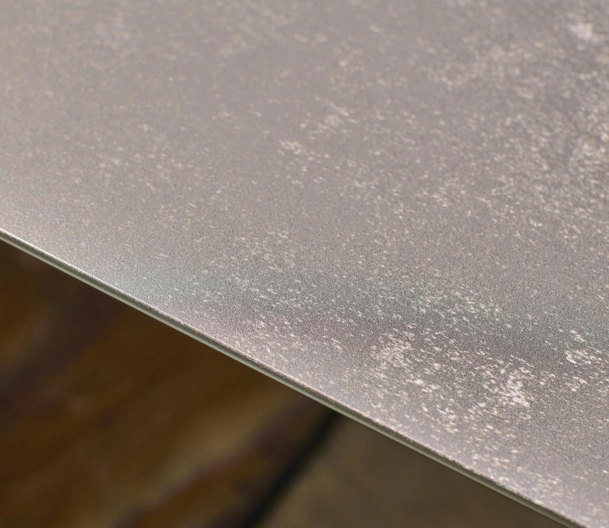 Close-up of a metal table edge with a textured finish, displaying a speckled metallic surface. Ideal for modern interiors, its durable design is both sleek and stylish.