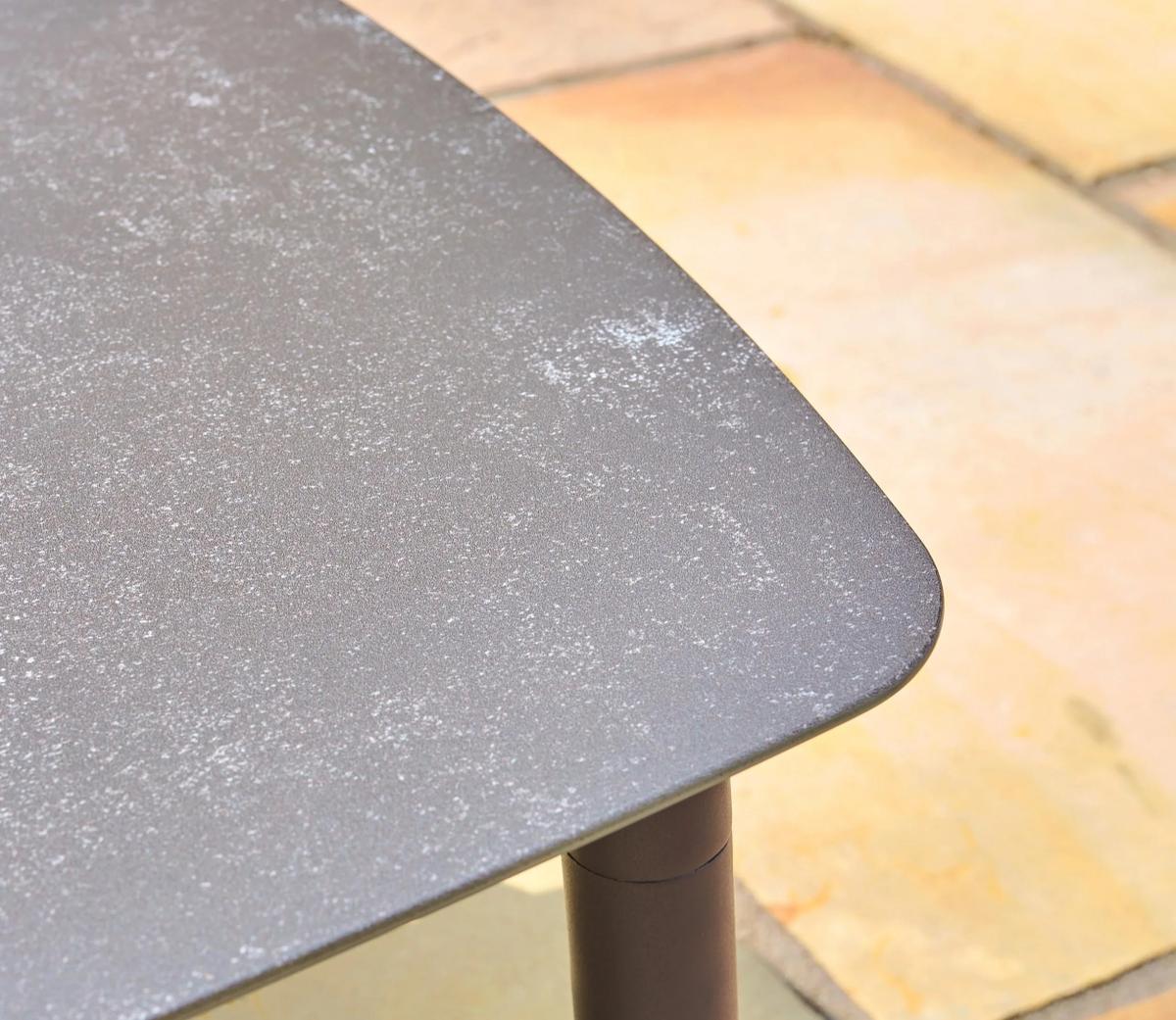 Modern outdoor table showing a close-up of the grey speckled rectangular tabletop, featuring smooth rounded edges, designed for durability and style in patio settings.