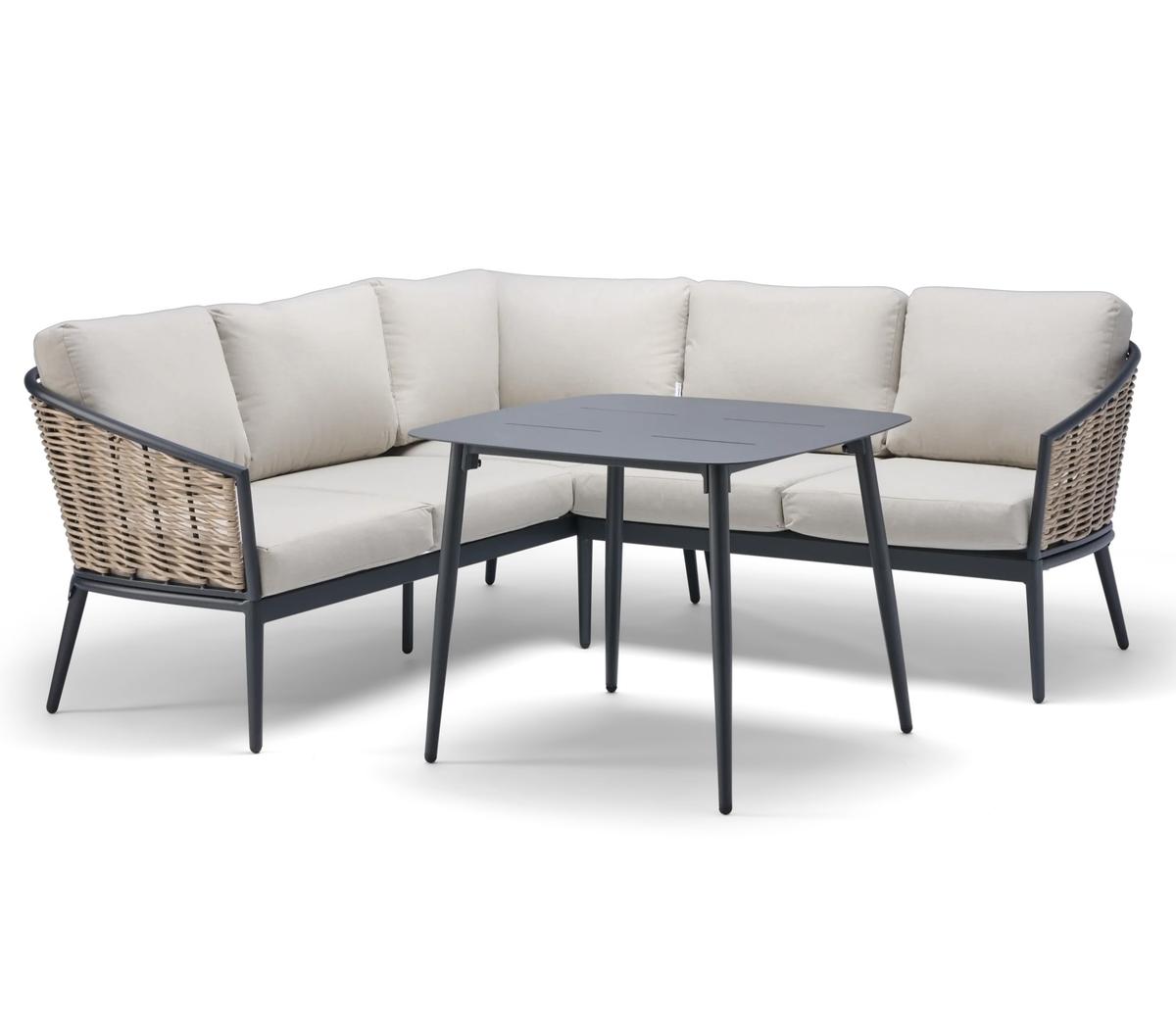 Outdoor rattan corner sofa set featuring beige cushioned seating and a sleek black metal table. Ideal for patios, gardens, and stylish alfresco dining spaces.