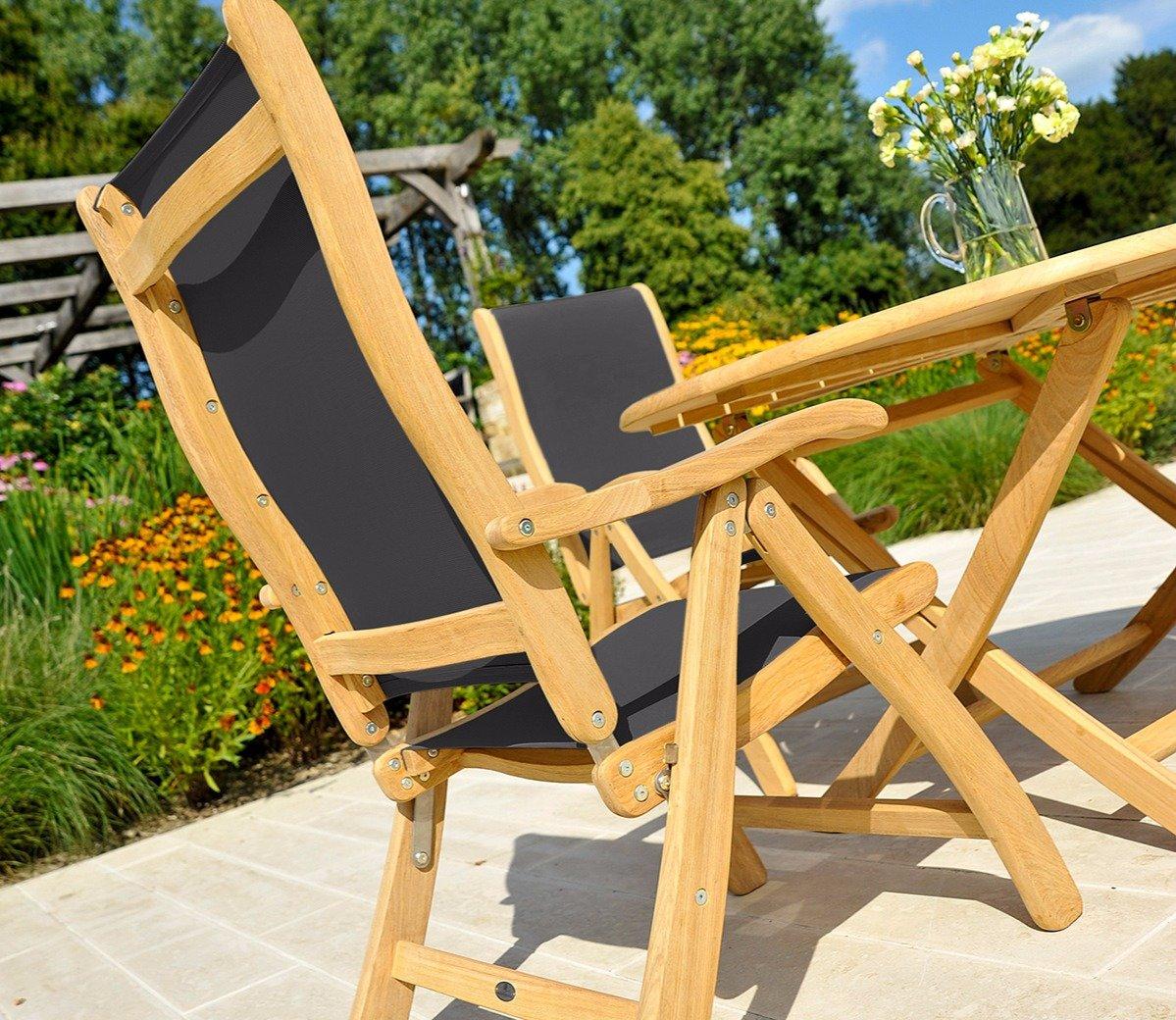 Wooden garden dining set featuring two reclining chairs with black fabric seats and a round table set on a sunny patio, surrounded by vibrant garden flowers.