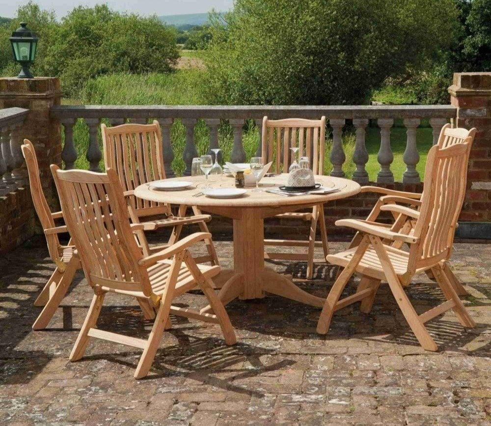 Round wooden garden table set with six chairs, elegantly arranged on a paved patio beside a stone balustrade, offering a serene outdoor dining experience.