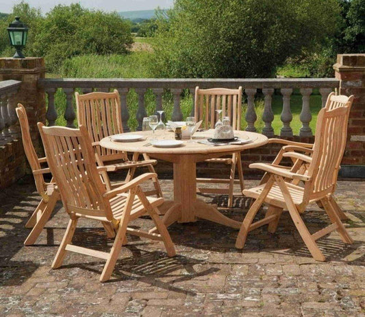 Round wooden garden table set with six chairs, elegantly arranged on a paved patio beside a stone balustrade, offering a serene outdoor dining experience.