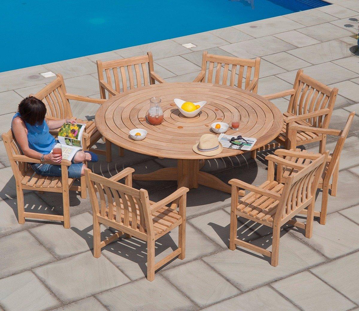 Teak outdoor dining set with round table and eight chairs by a poolside. A person seated with a magazine and drink, showcasing a relaxed summer vibe.