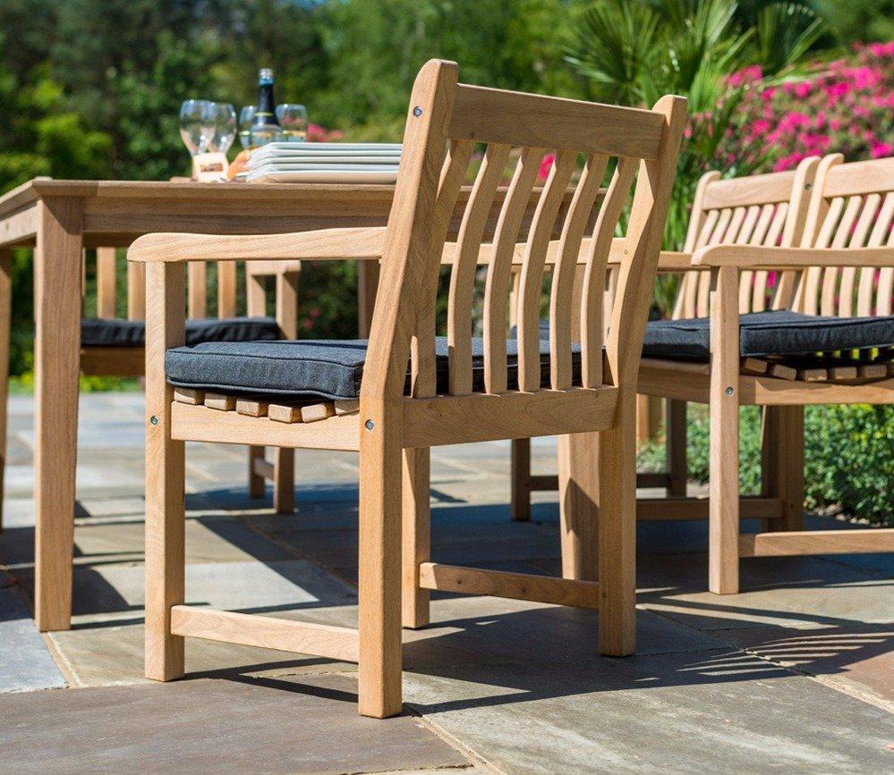 Outdoor dining set featuring a sturdy teak wood chair with grey cushion, paired with a matching table. Ideal for patios and garden spaces, set against a lush green backdrop.