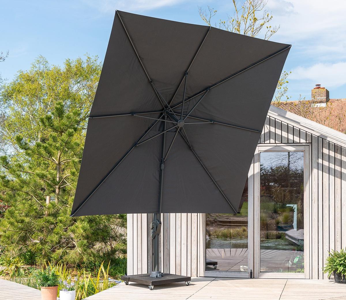 Cantilever parasol viewed from underneath showing sturdy frame and ribs, positioned on a wooden deck beside a contemporary garden room for stylish outdoor shade.