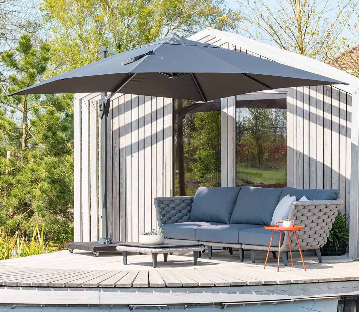 Stylish cantilever parasol shading outdoor sofa set on decking, perfect for creating comfortable shaded garden seating area beside contemporary garden room.