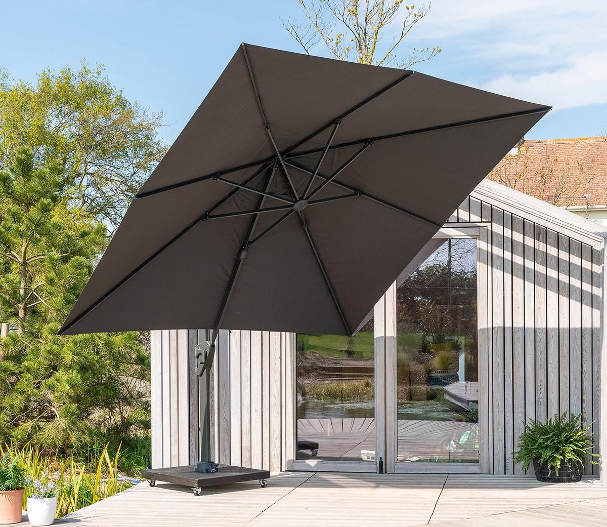 Side arm parasol extended over wooden decking, positioned beside modern garden building with glass doors, offering adjustable shade for outdoor living areas.