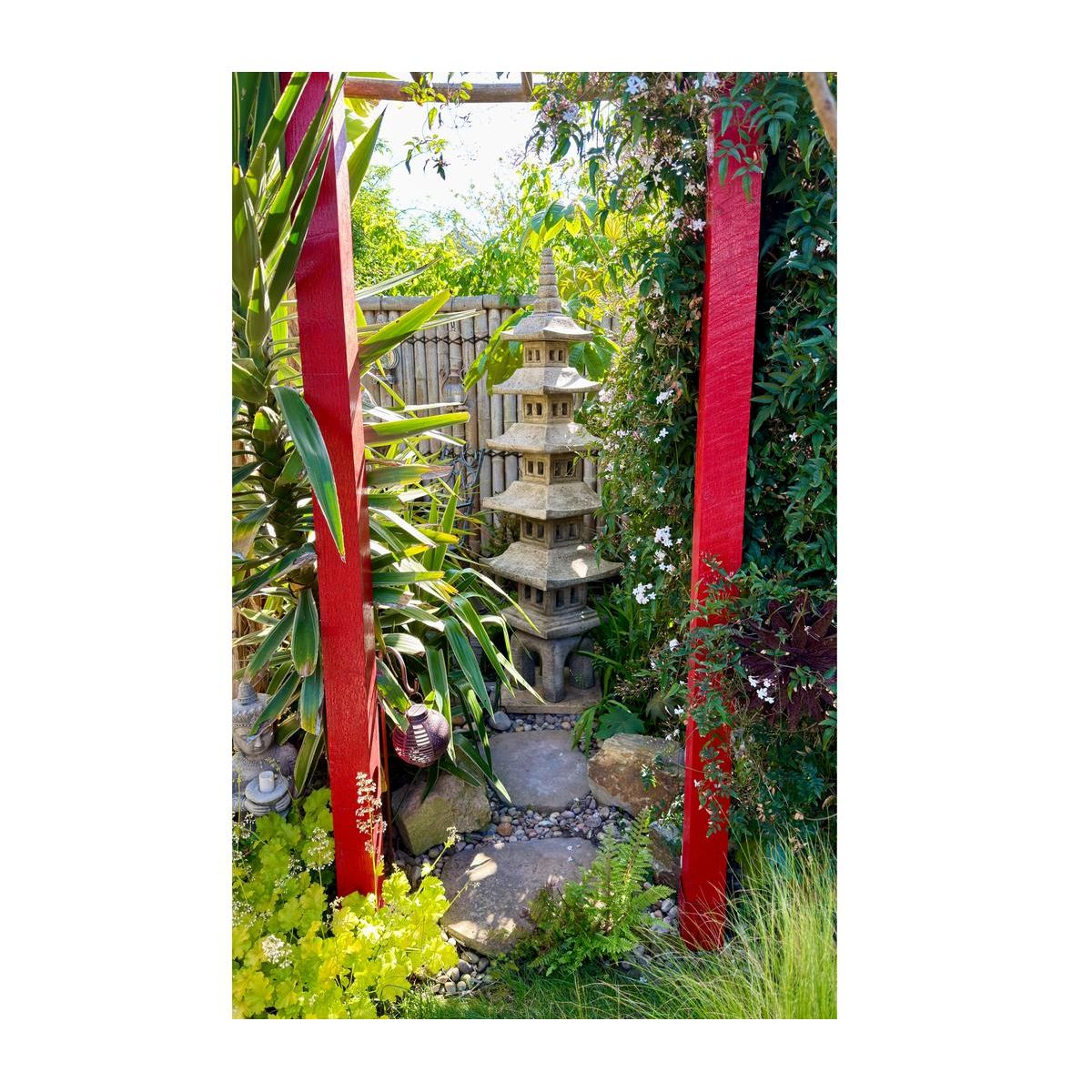 A serene Japanese garden showcasing a traditional stone pagoda and a white Buddha statue amidst lush greenery, providing a tranquil and spiritual atmosphere.