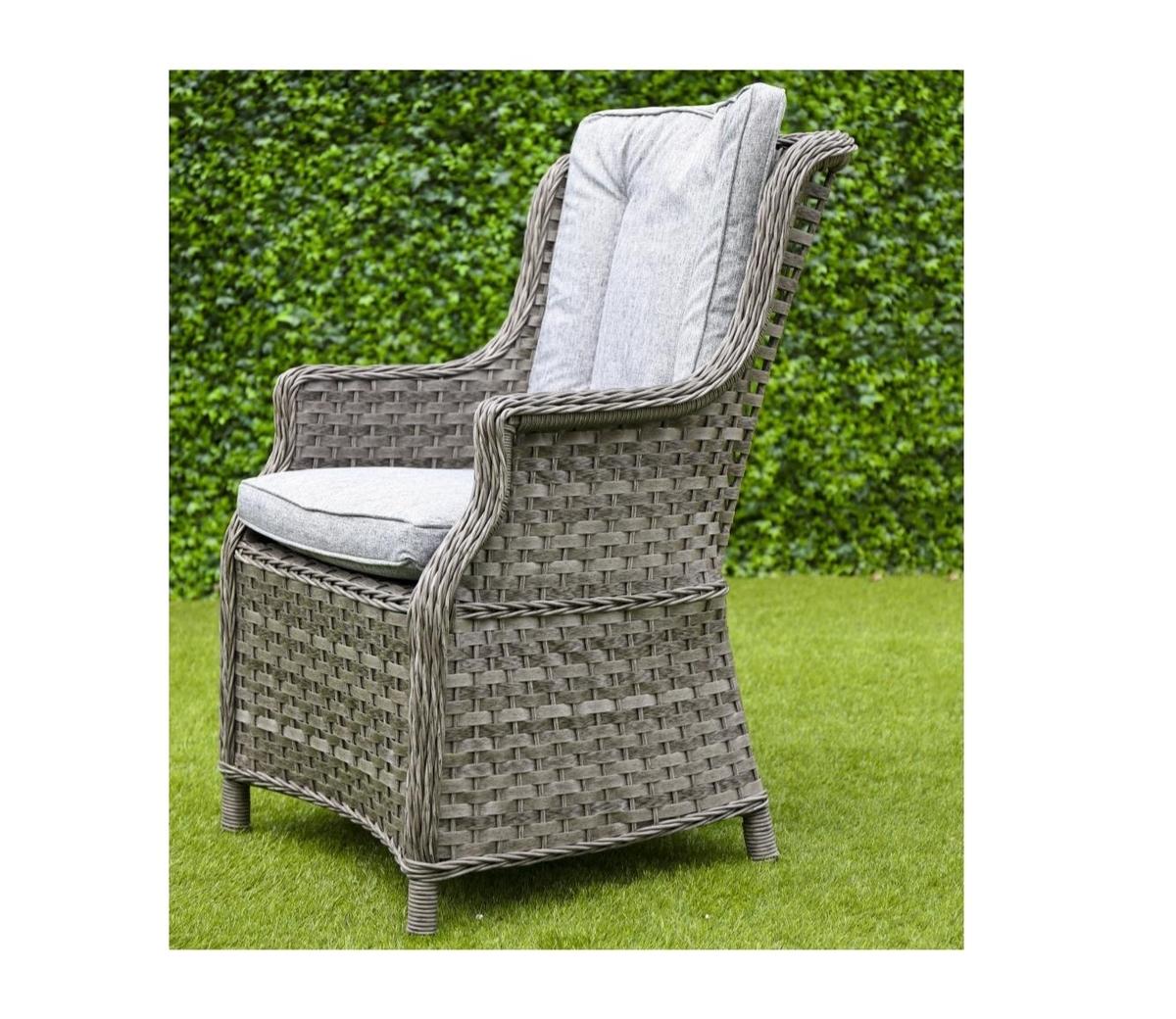 Grey rattan garden chair with padded cushions, designed for outdoor comfort. Set on a lush green lawn with a hedge backdrop, perfect for stylish patios.