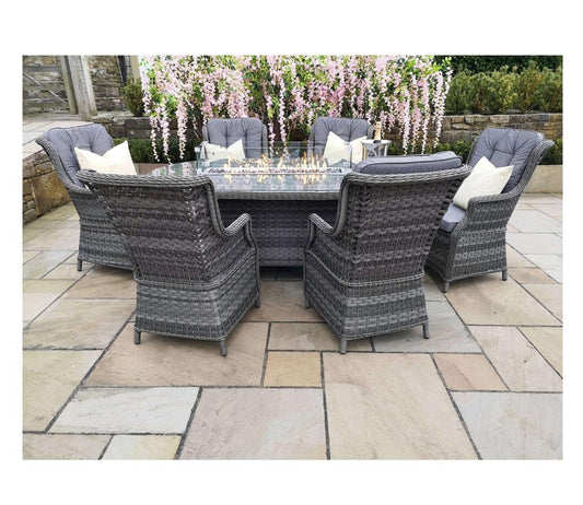 Outdoor rattan dining set featuring six cushioned chairs and a glass-top table, surrounded by blooming pink flowers on a stone patio, perfect for gatherings.