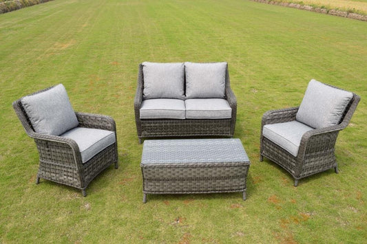 Outdoor wicker furniture set featuring a two-seater sofa, two armchairs, and a rectangular coffee table with grey cushions, displayed on a green lawn.
