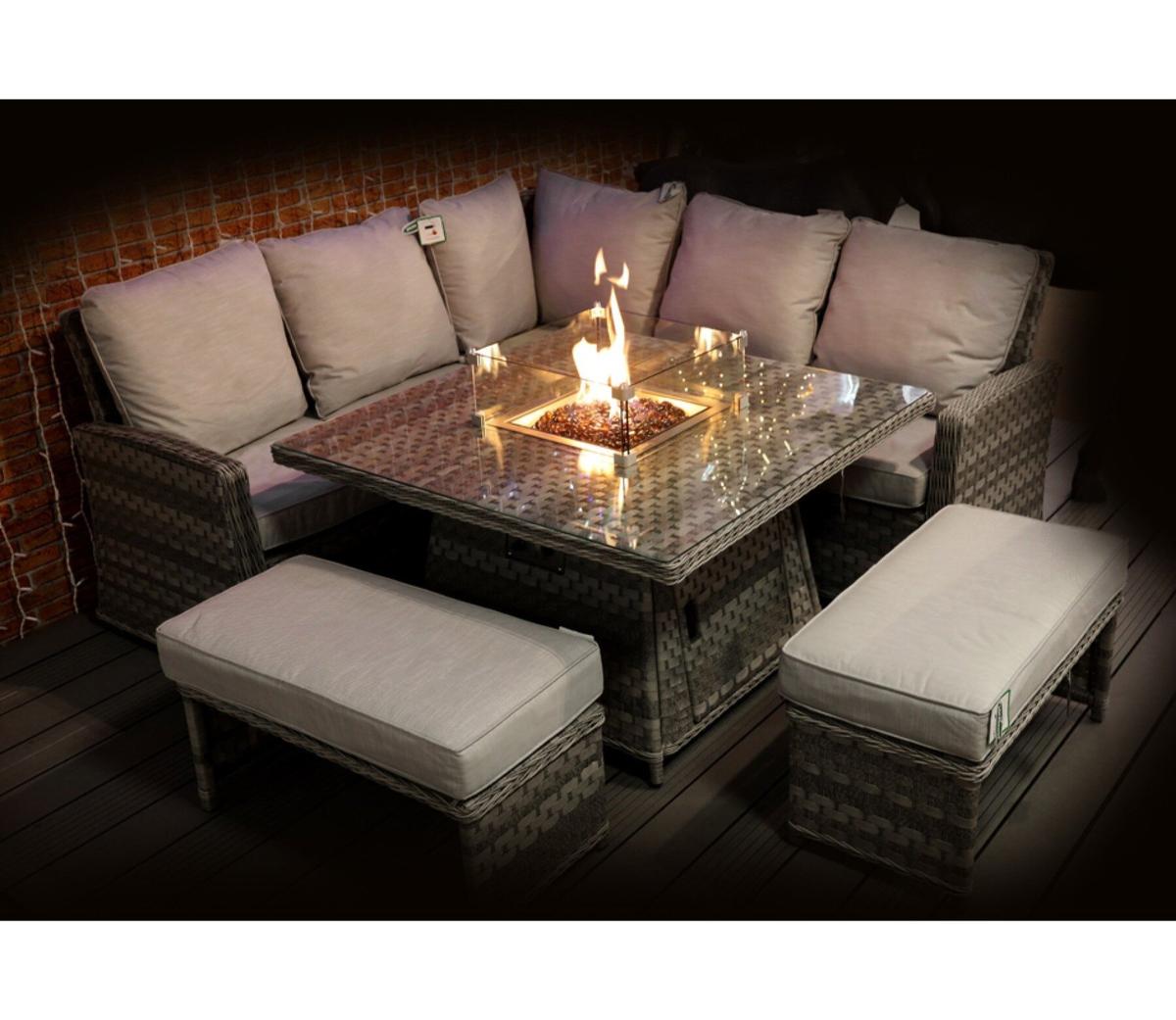 Outdoor patio sofa set with a glass tabletop and integrated fire pit, surrounded by comfortable grey cushions, perfect for alfresco evenings and garden gatherings.